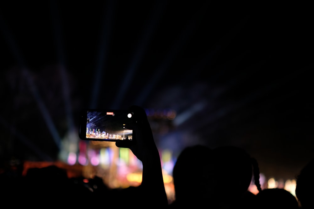 a person taking a picture with a cell phone at a concert