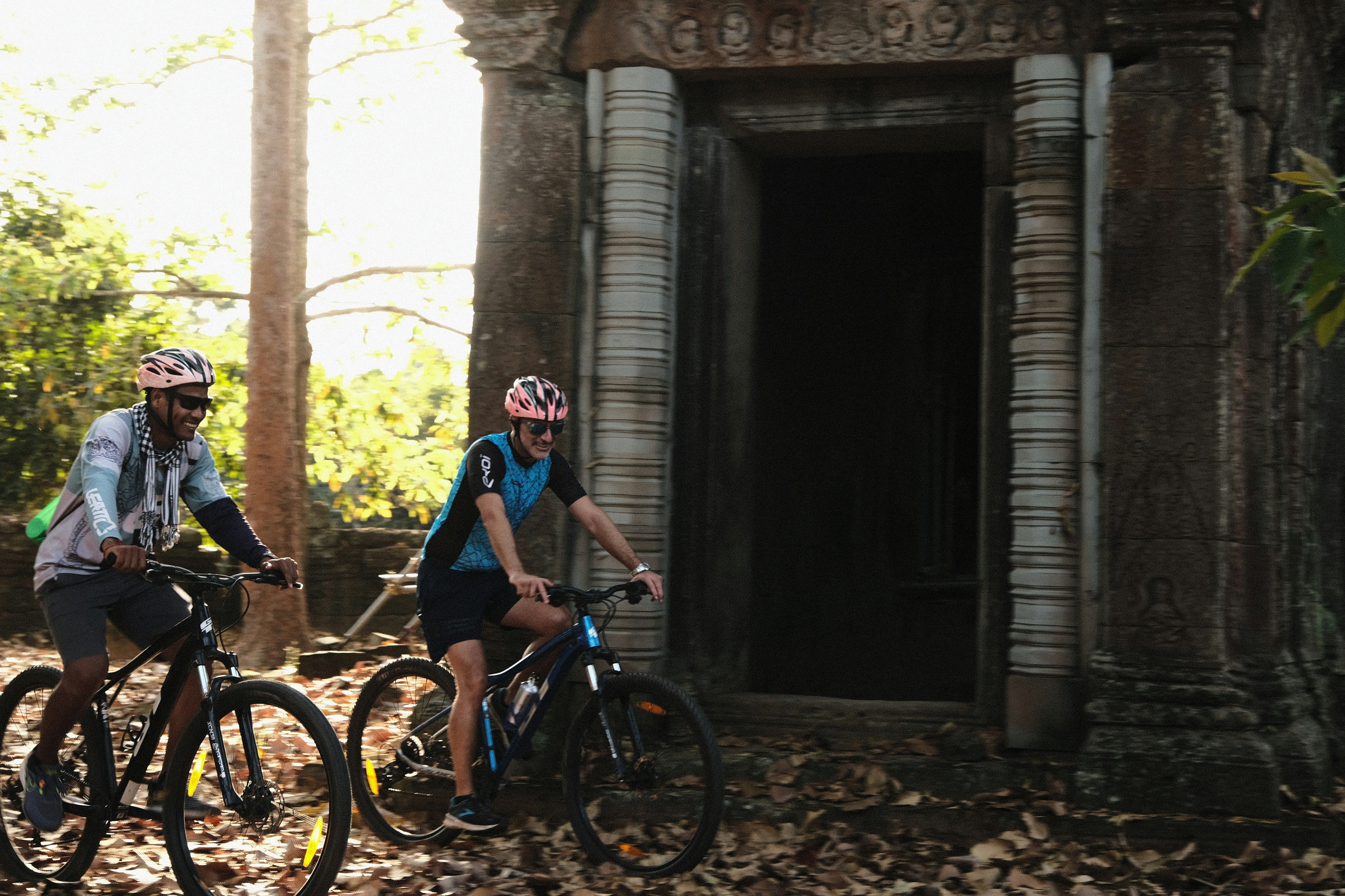 a couple of people riding bikes through a forest
