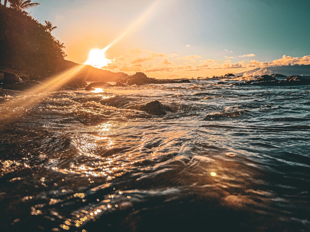 the sun is setting over the water at the beach