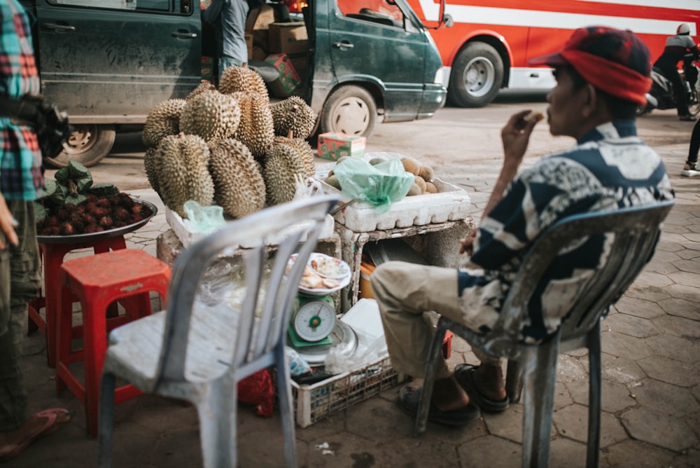 a man sitting in a chair next to a pile of fruit