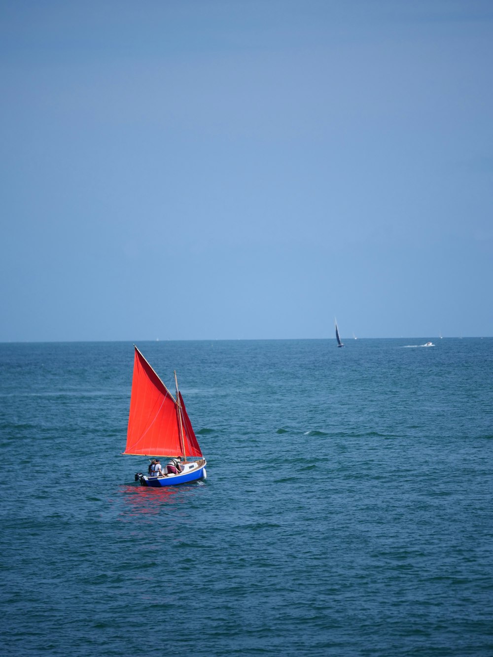 a red sailboat in the middle of the ocean