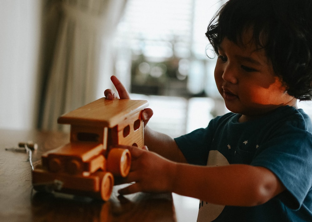a young child playing with a wooden toy truck