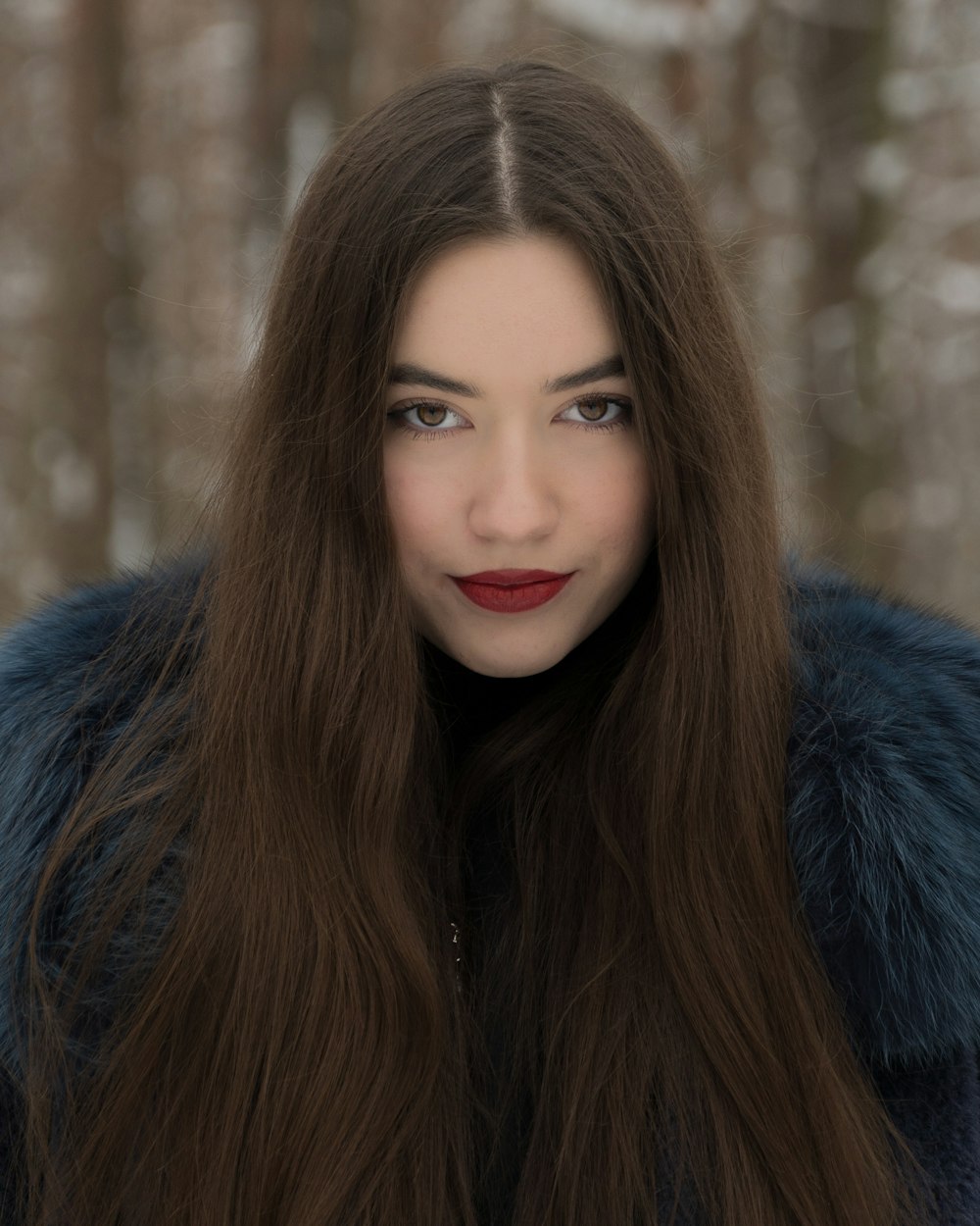 a woman with long brown hair wearing a fur coat