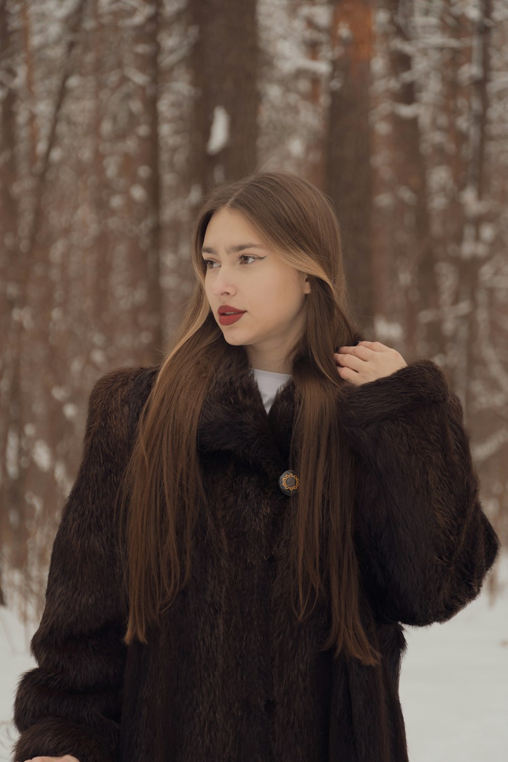 a woman in a fur coat standing in the snow