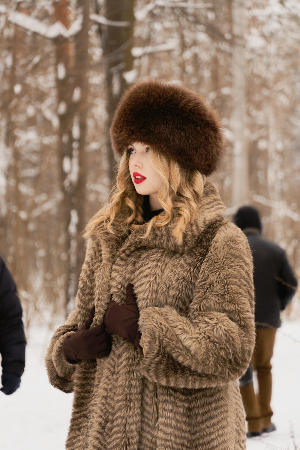 a woman standing in the snow wearing a fur hat