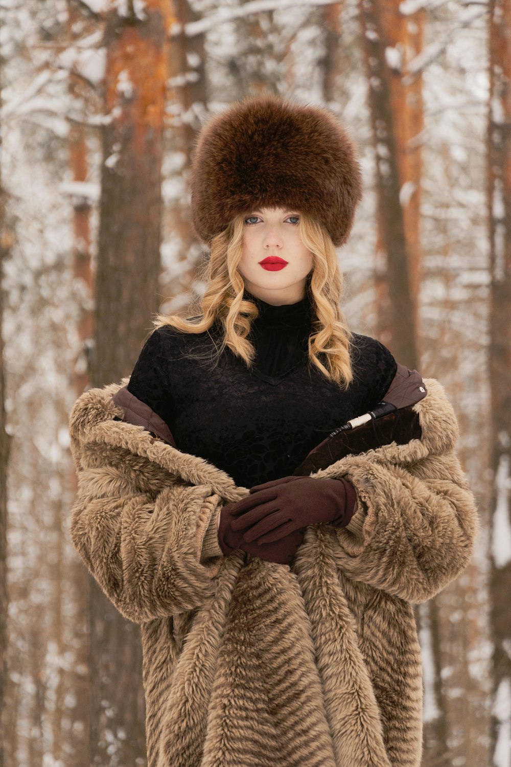 a woman in a fur coat and hat standing in the snow
