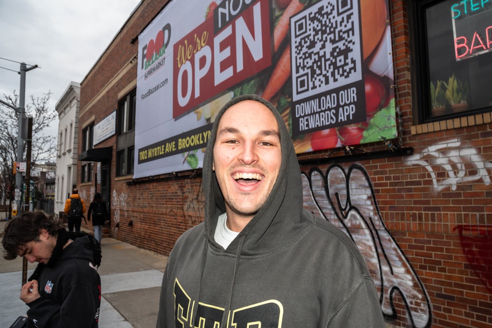 a man in a hoodie standing in front of a building