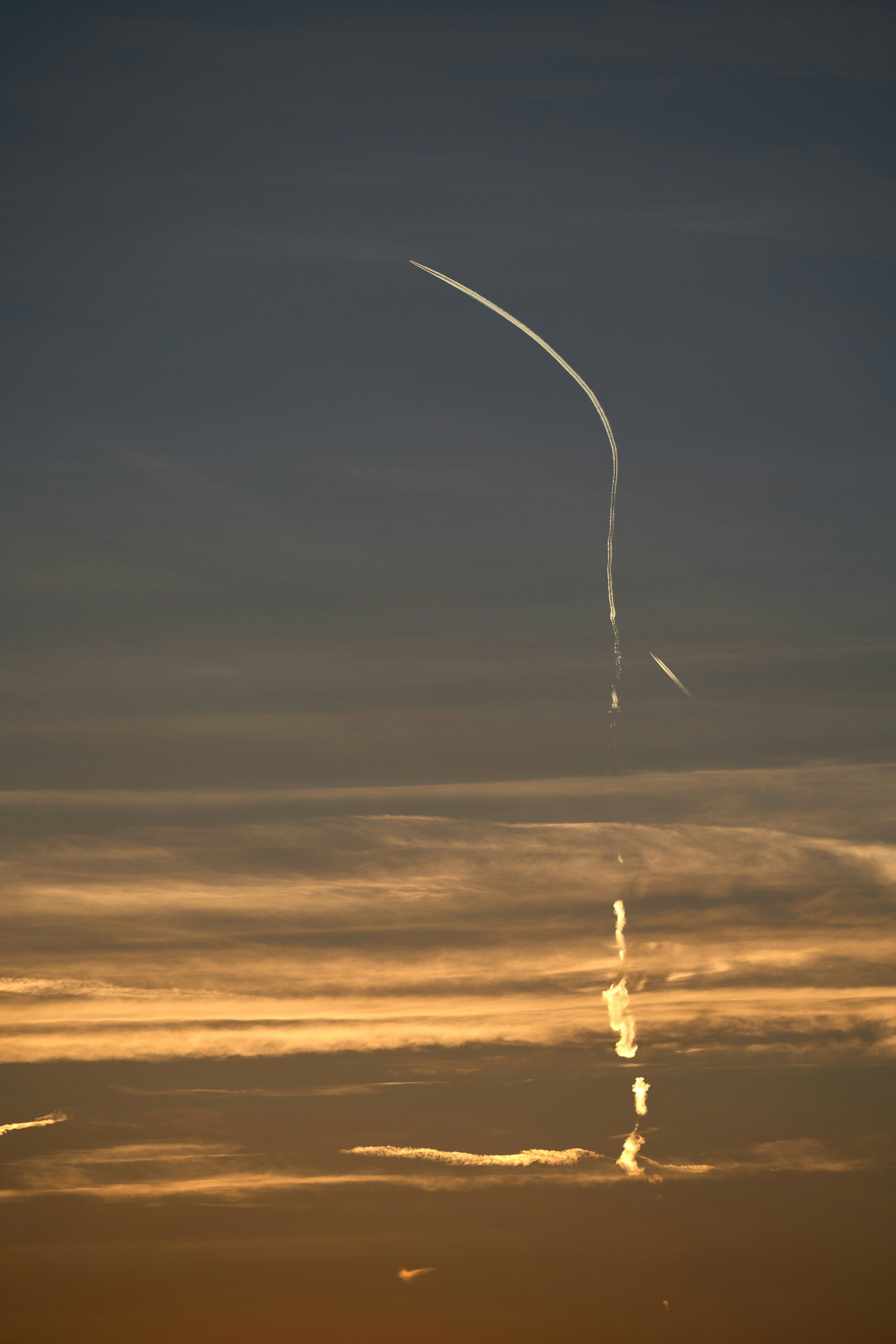 an airplane is flying in the sky at sunset