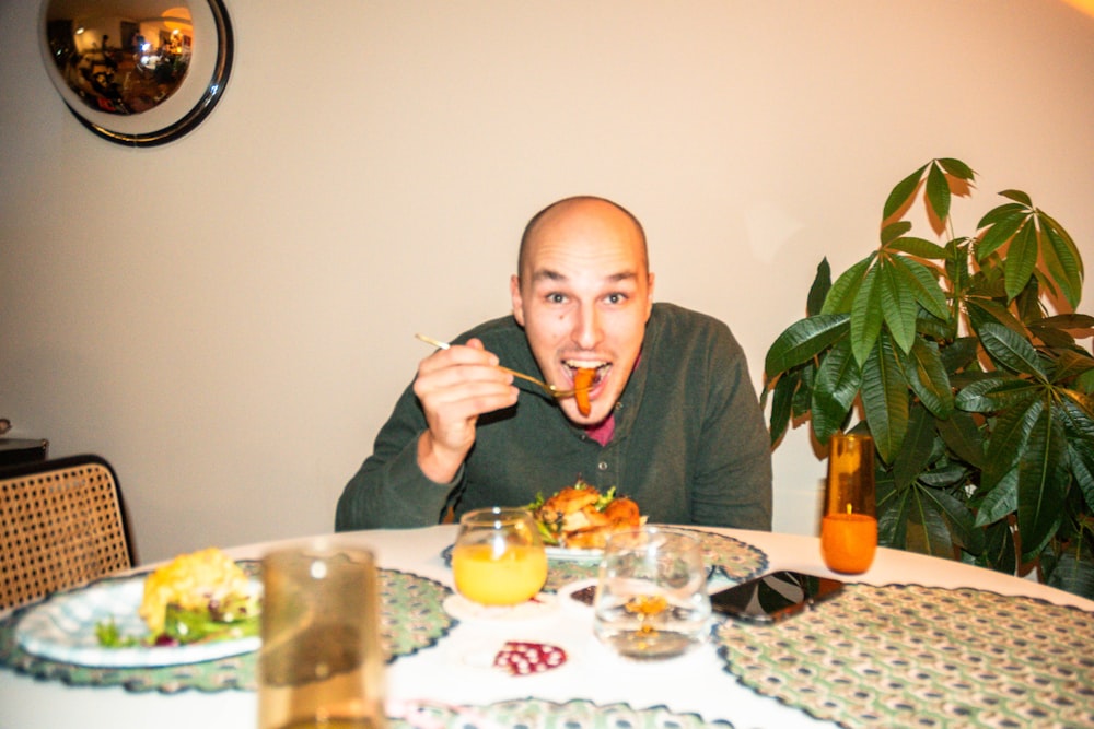 Un hombre sentado en una mesa con un plato de comida frente a él