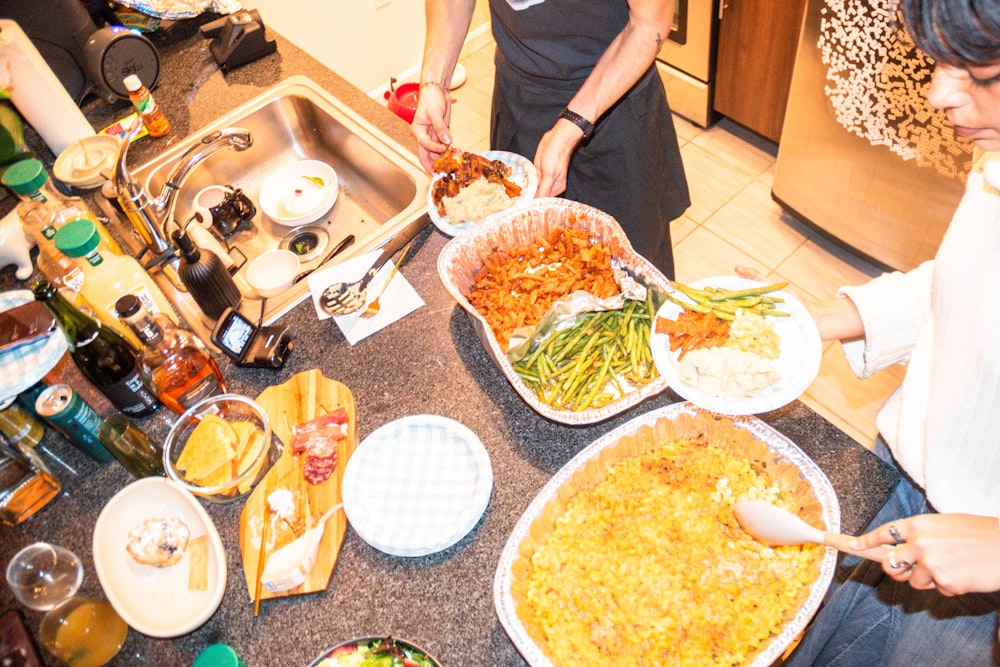 a group of people standing around a table filled with food