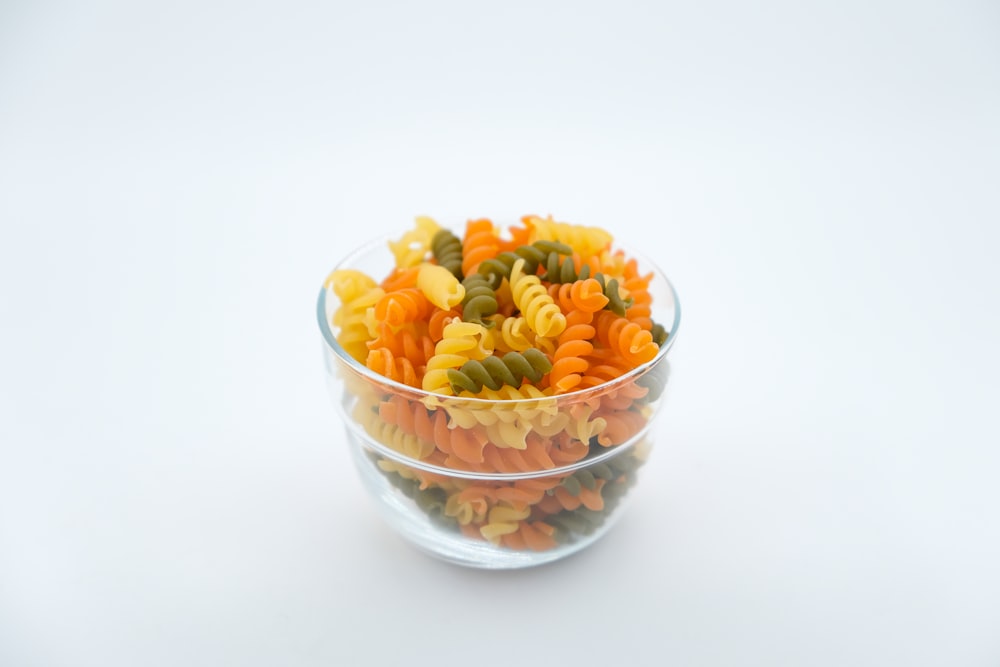 a glass bowl filled with pasta and veggies