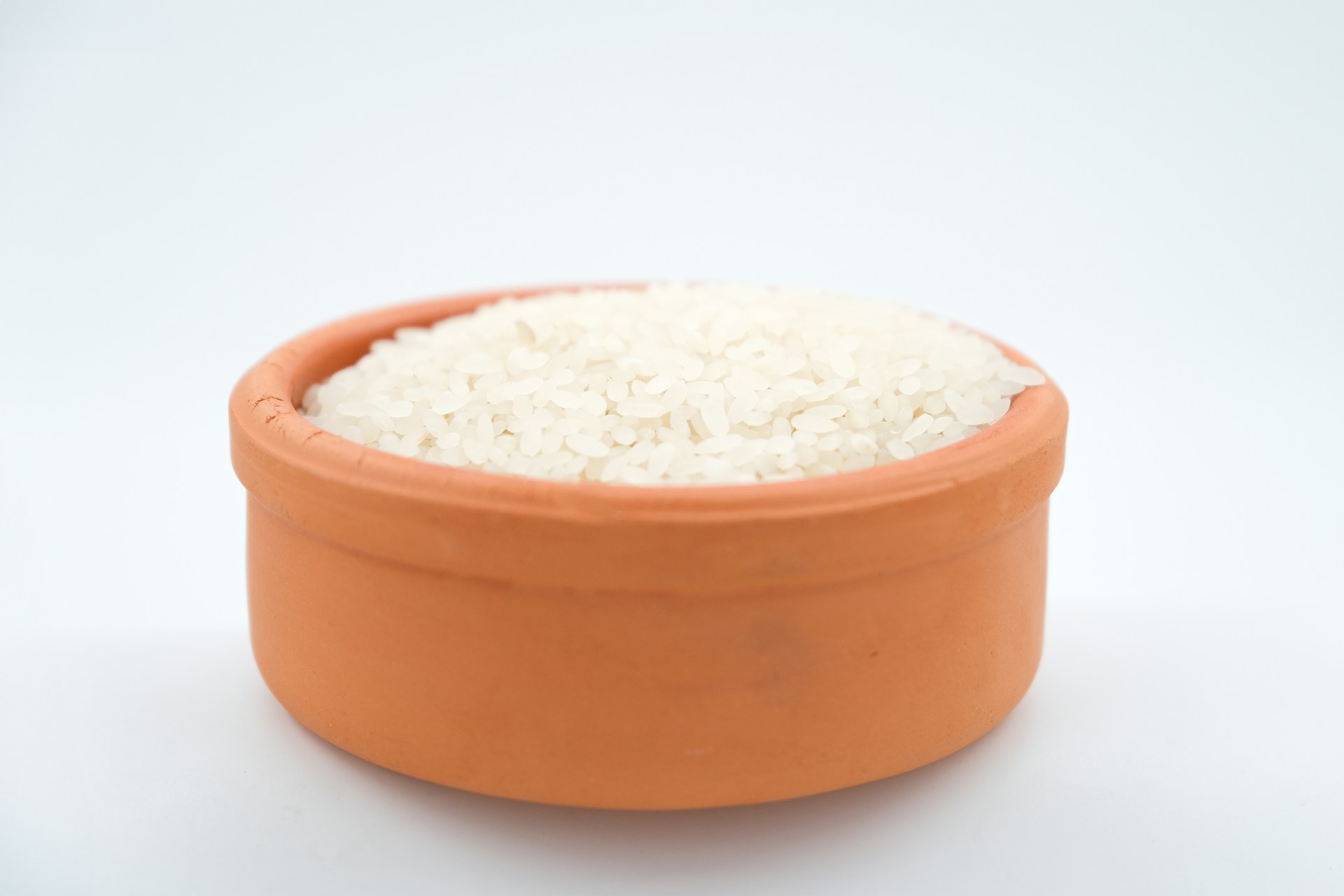 a brown bowl filled with white rice on a white surface