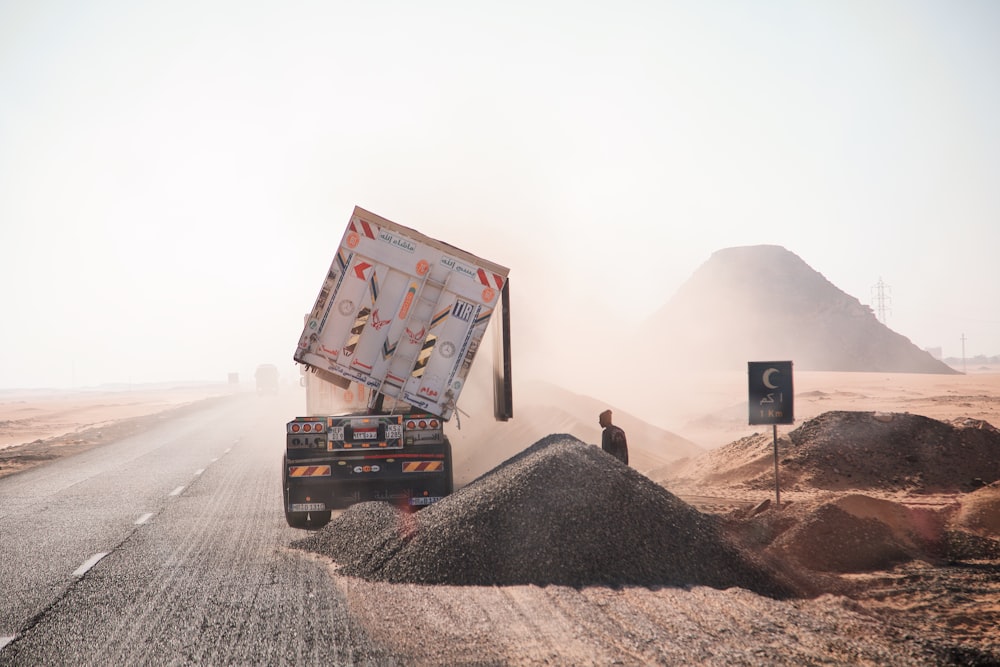 土の山の横の未舗装の道路を走るトラック