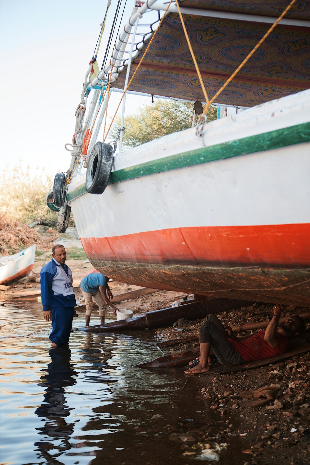 um homem parado ao lado de um barco em um corpo de água