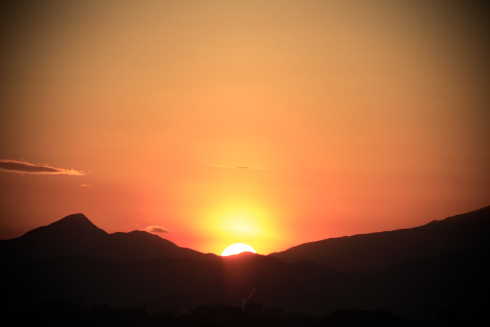 the sun is setting over a mountain range