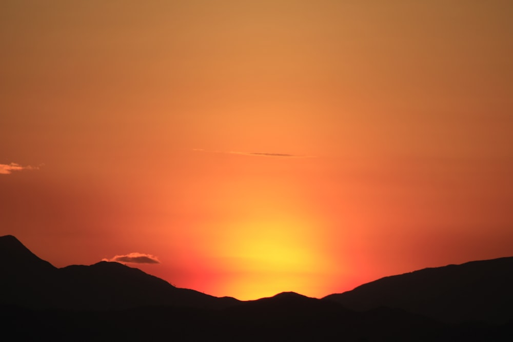 the sun is setting over a mountain range