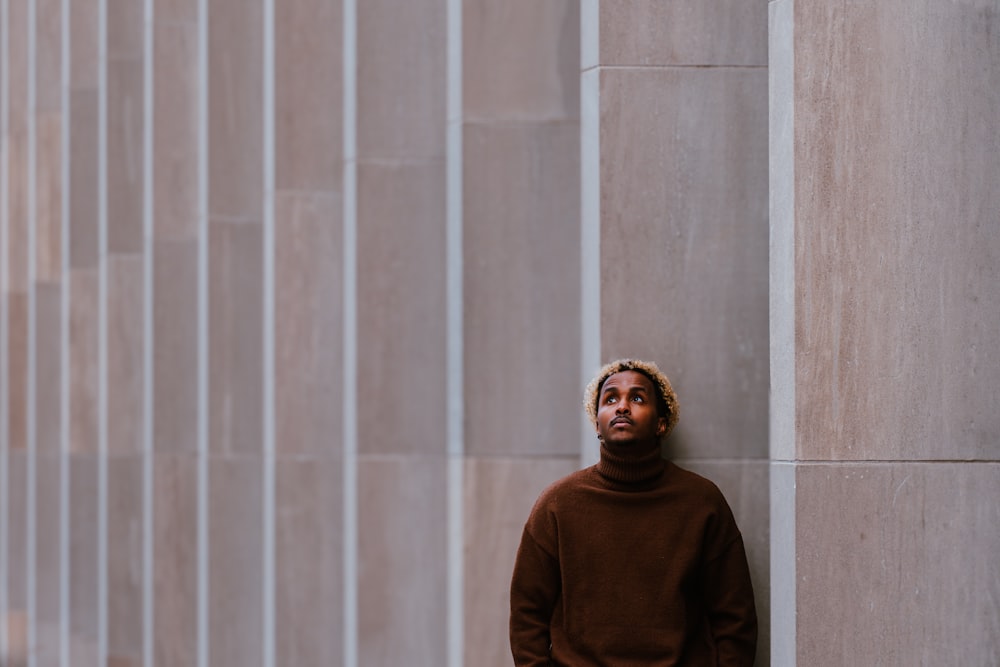 a man leaning against a wall in front of a building