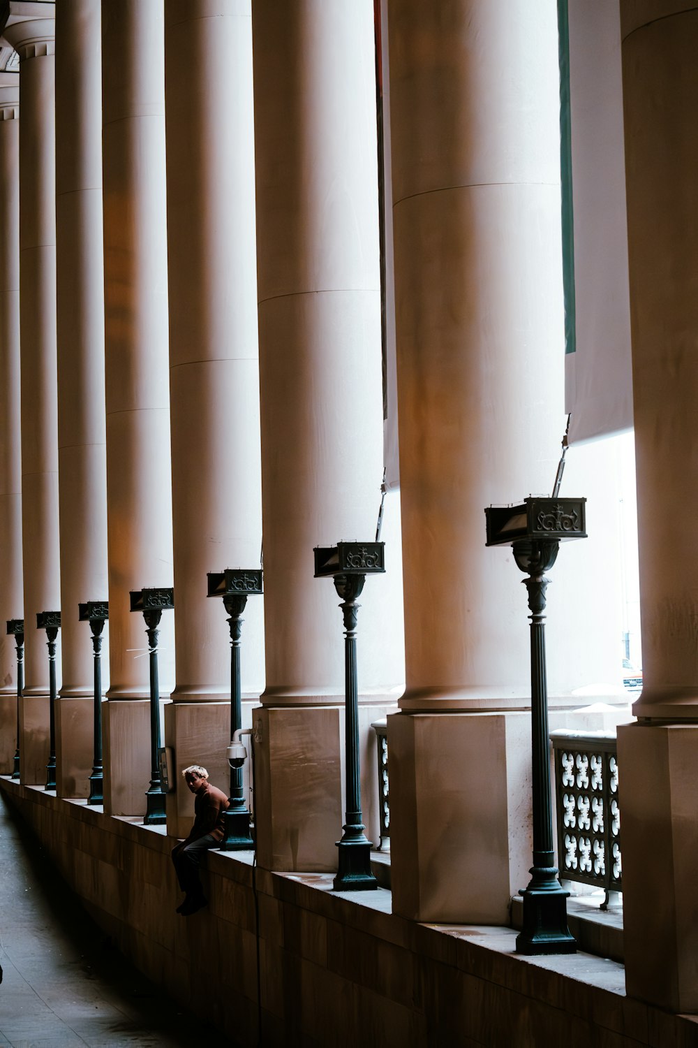 a person sitting on a bench next to a row of pillars