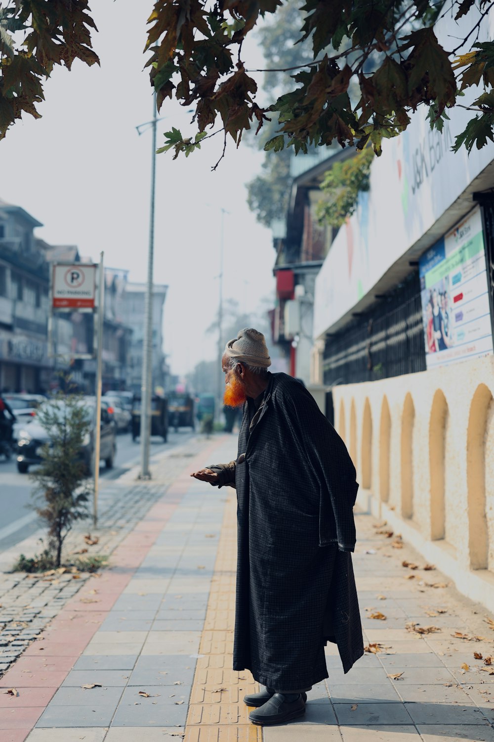 a man standing on a sidewalk next to a tree