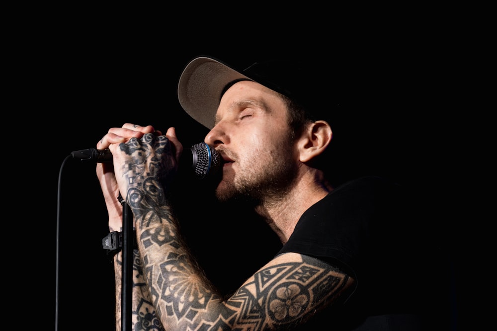 a man with tattoos on his arms and arms holding a microphone