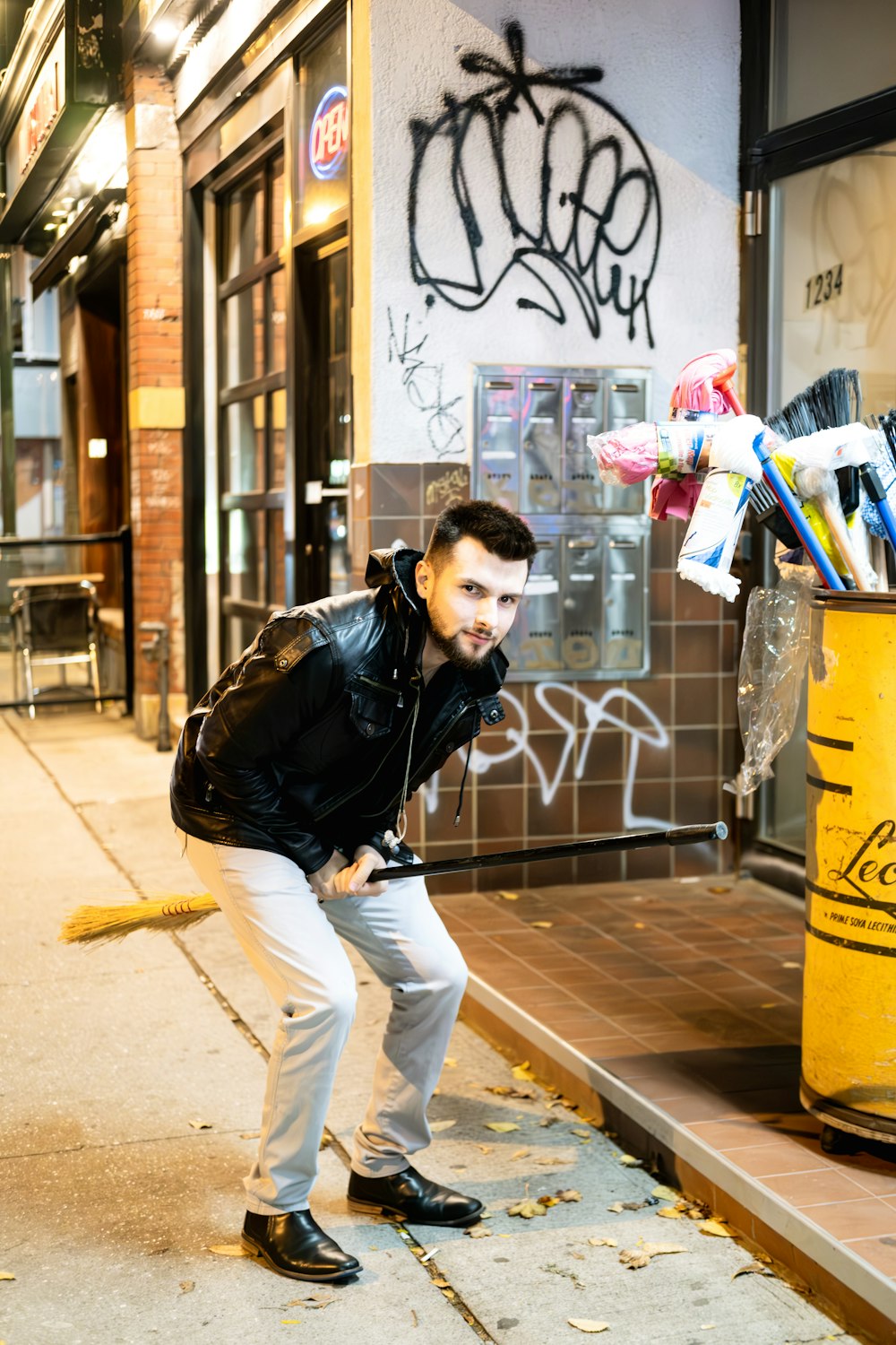 a man leaning against a trash can on a sidewalk