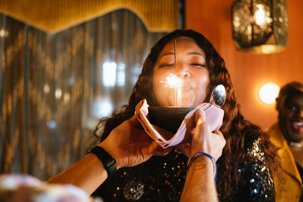 a woman blowing out a sparkler on top of a cake