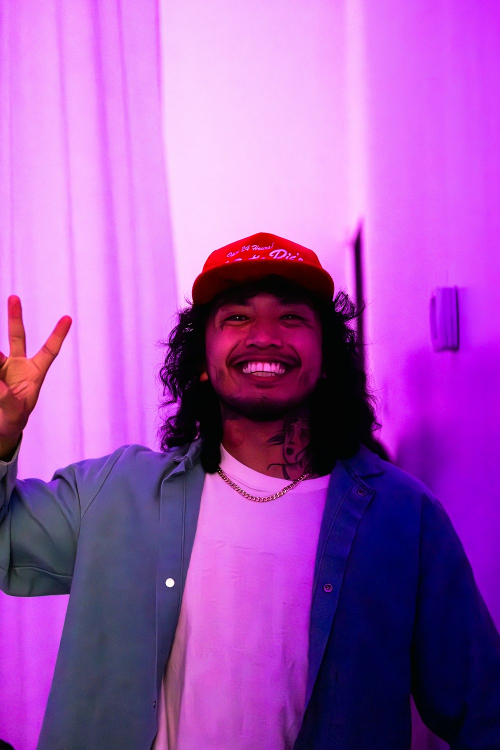 un hombre con el pelo largo y un sombrero rojo haciendo el signo de la paz