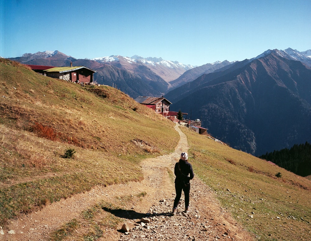 uma pessoa em pé em uma estrada de terra nas montanhas