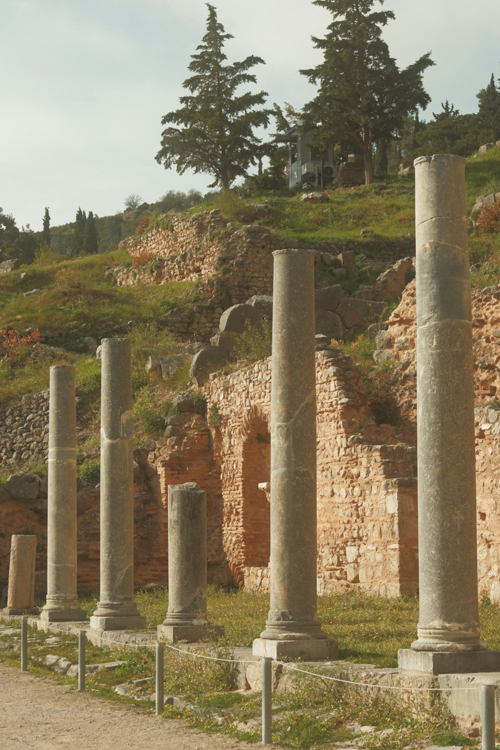 a row of stone pillars sitting next to a lush green hillside