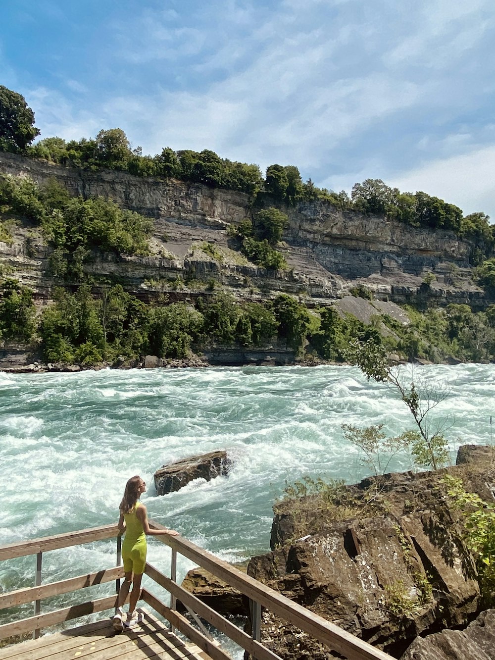 a woman standing on a wooden bridge over a river