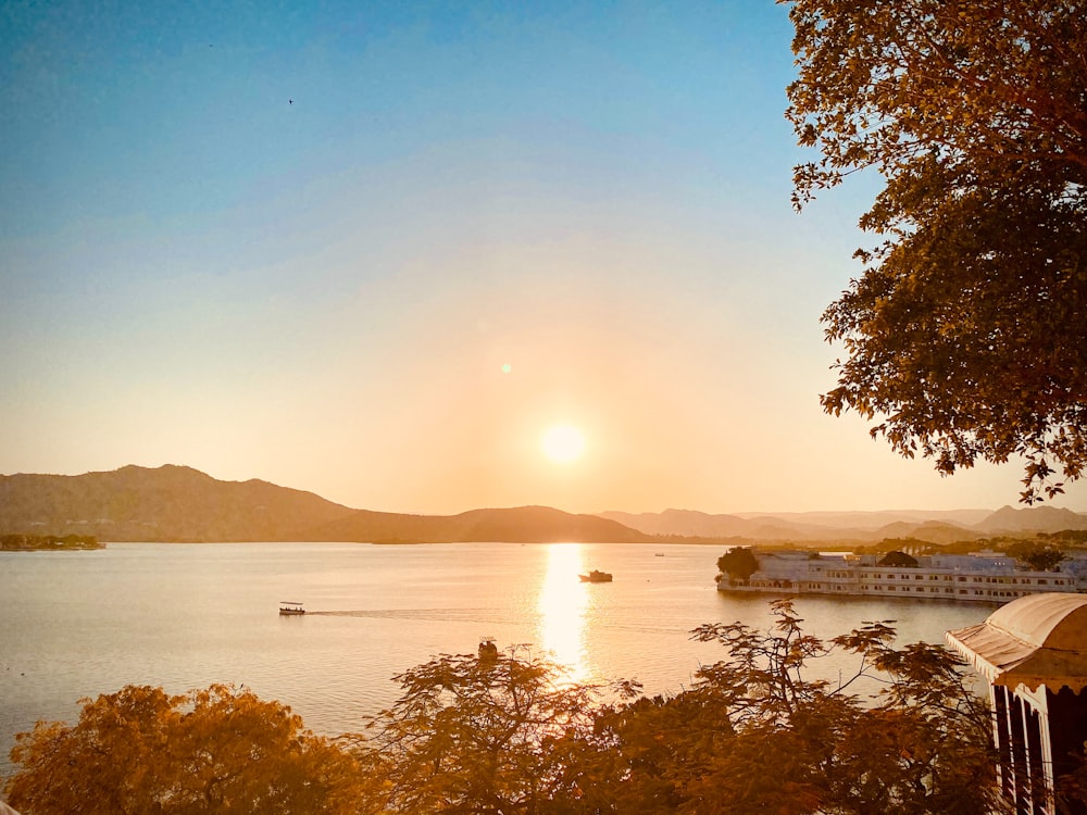 the sun is setting over a lake with boats in it