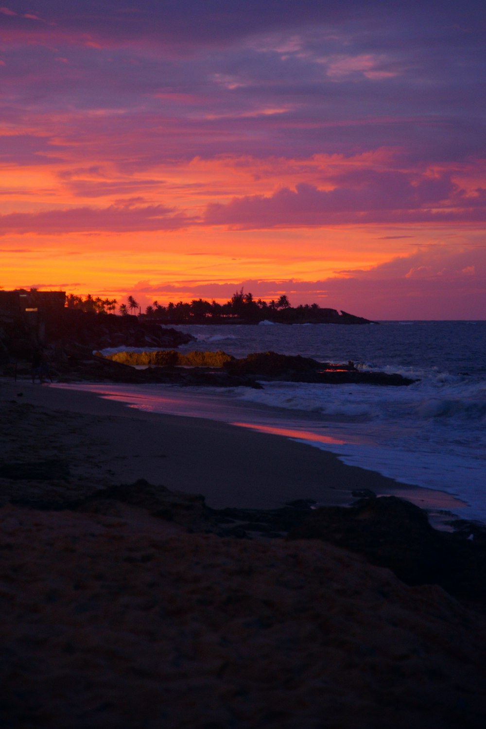 a sunset view of a beach with houses in the distance