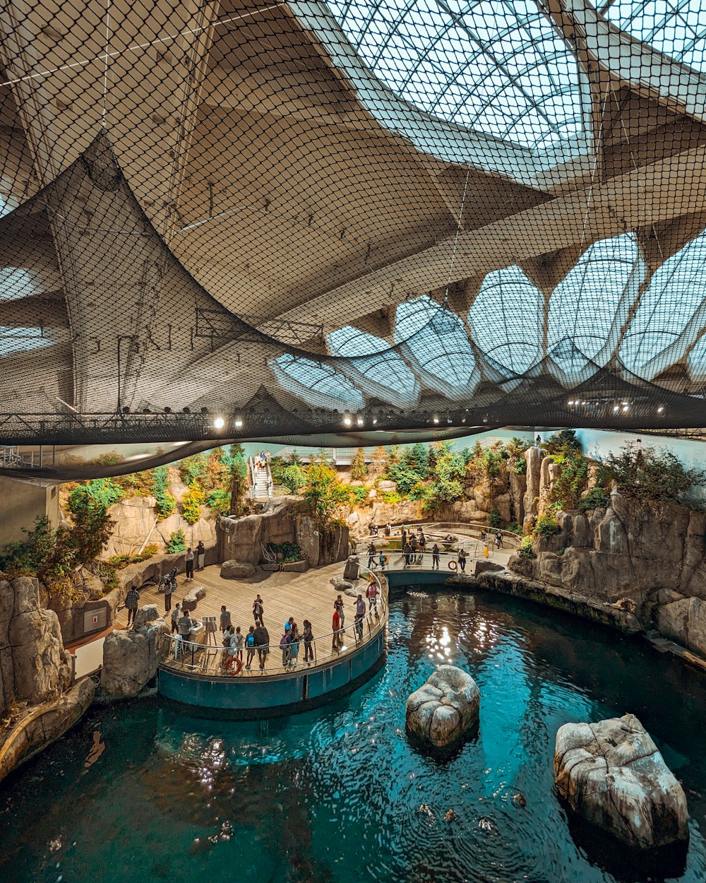 a group of people standing around a pond inside of a building