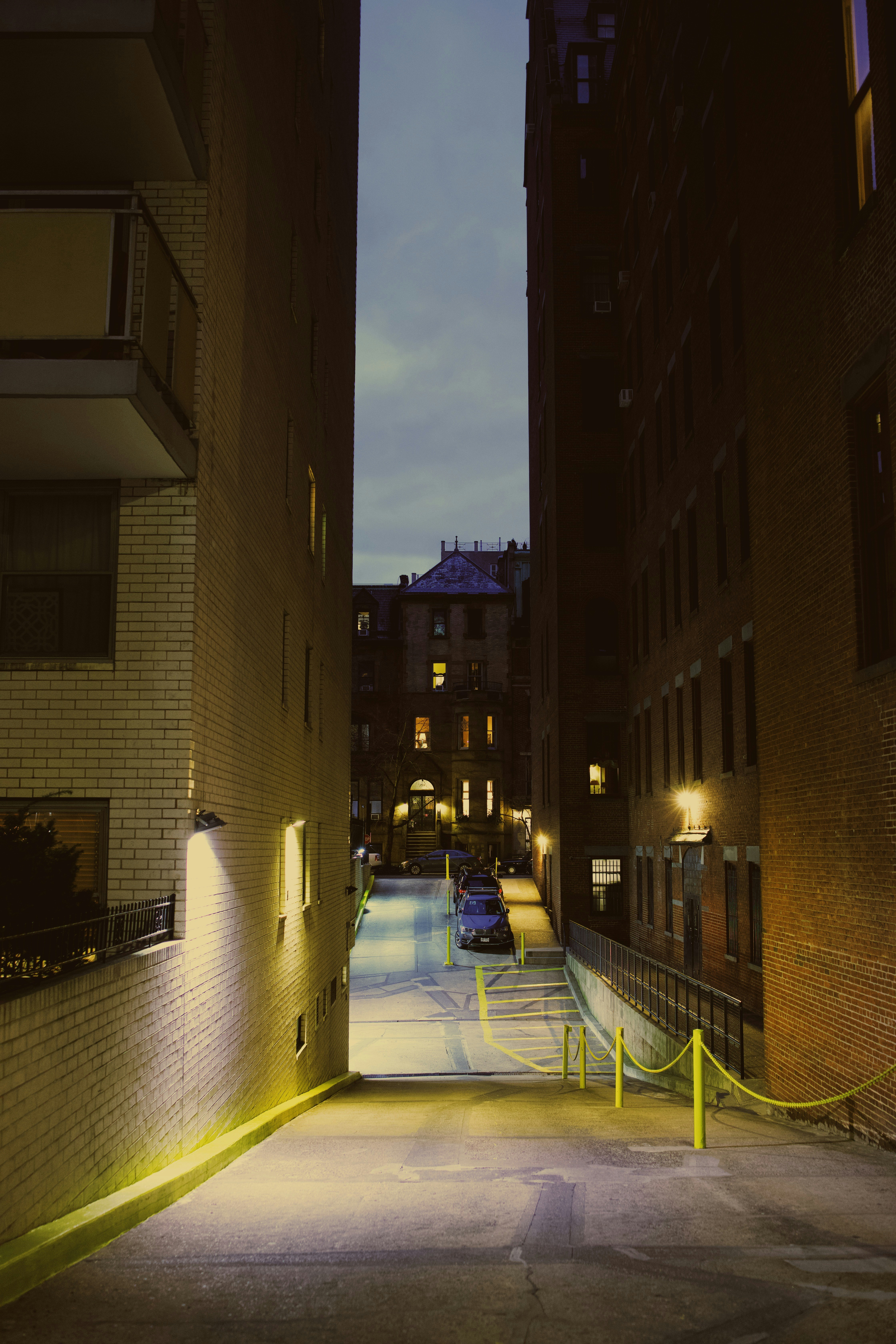A city street at night with cars parked on the side of the road photo ...