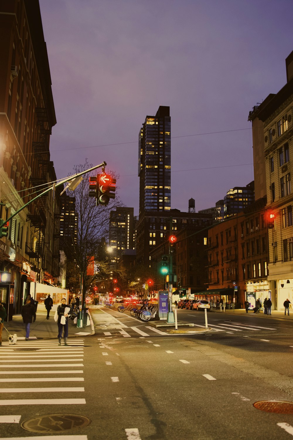 a city street at night with people crossing the street