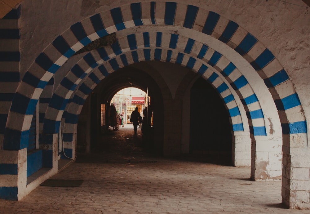 a person walking through a tunnel with blue and white stripes