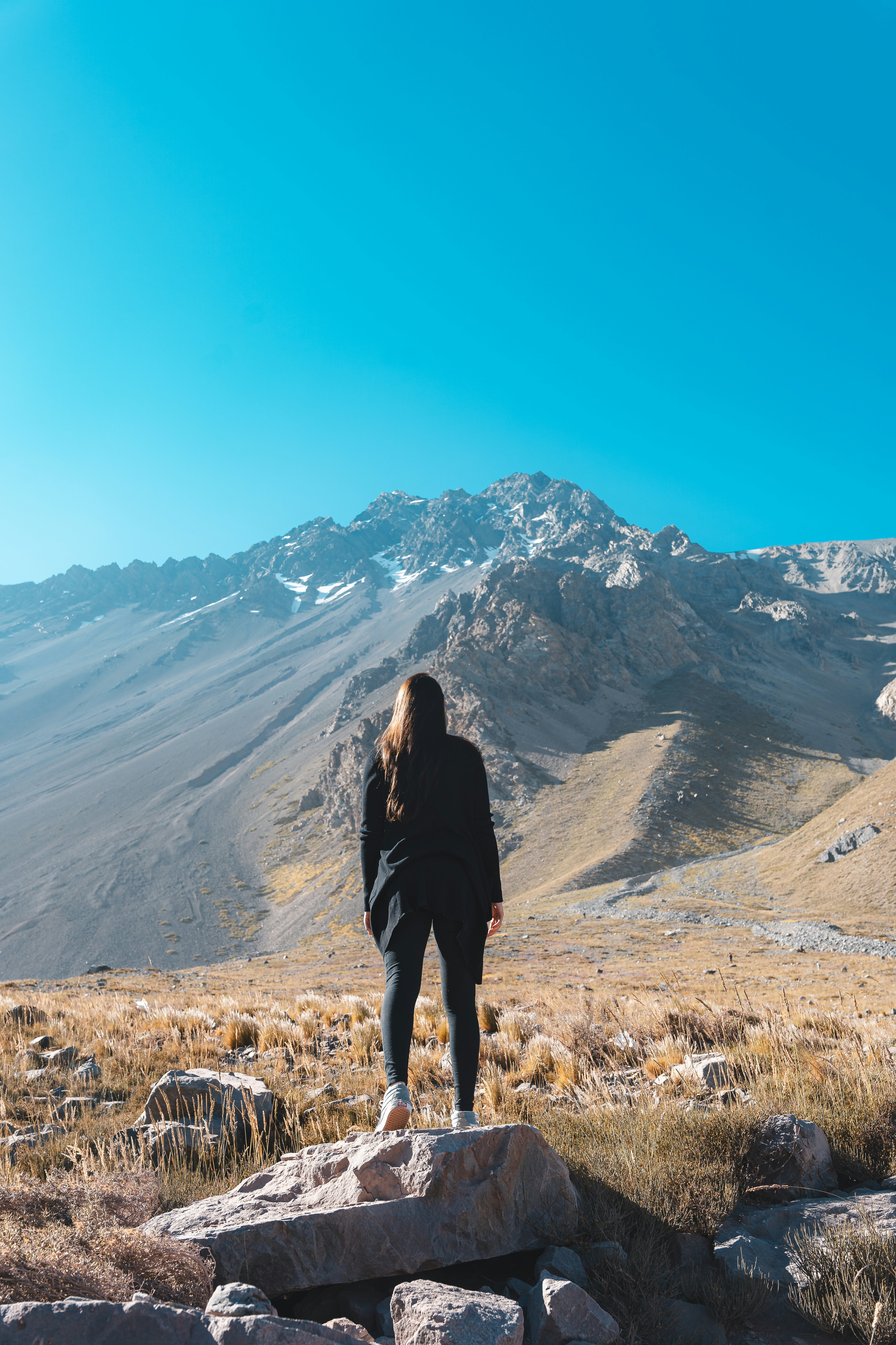 a woman standing on top of a rock covered hillside
