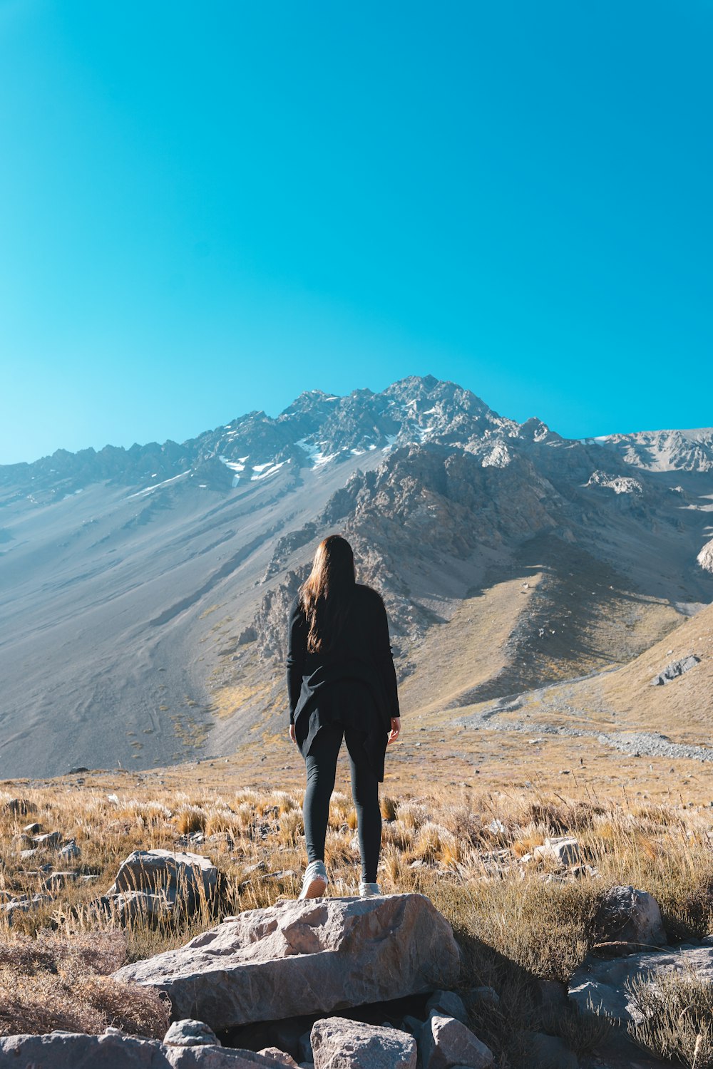 una donna in piedi sulla cima di una collina coperta di roccia