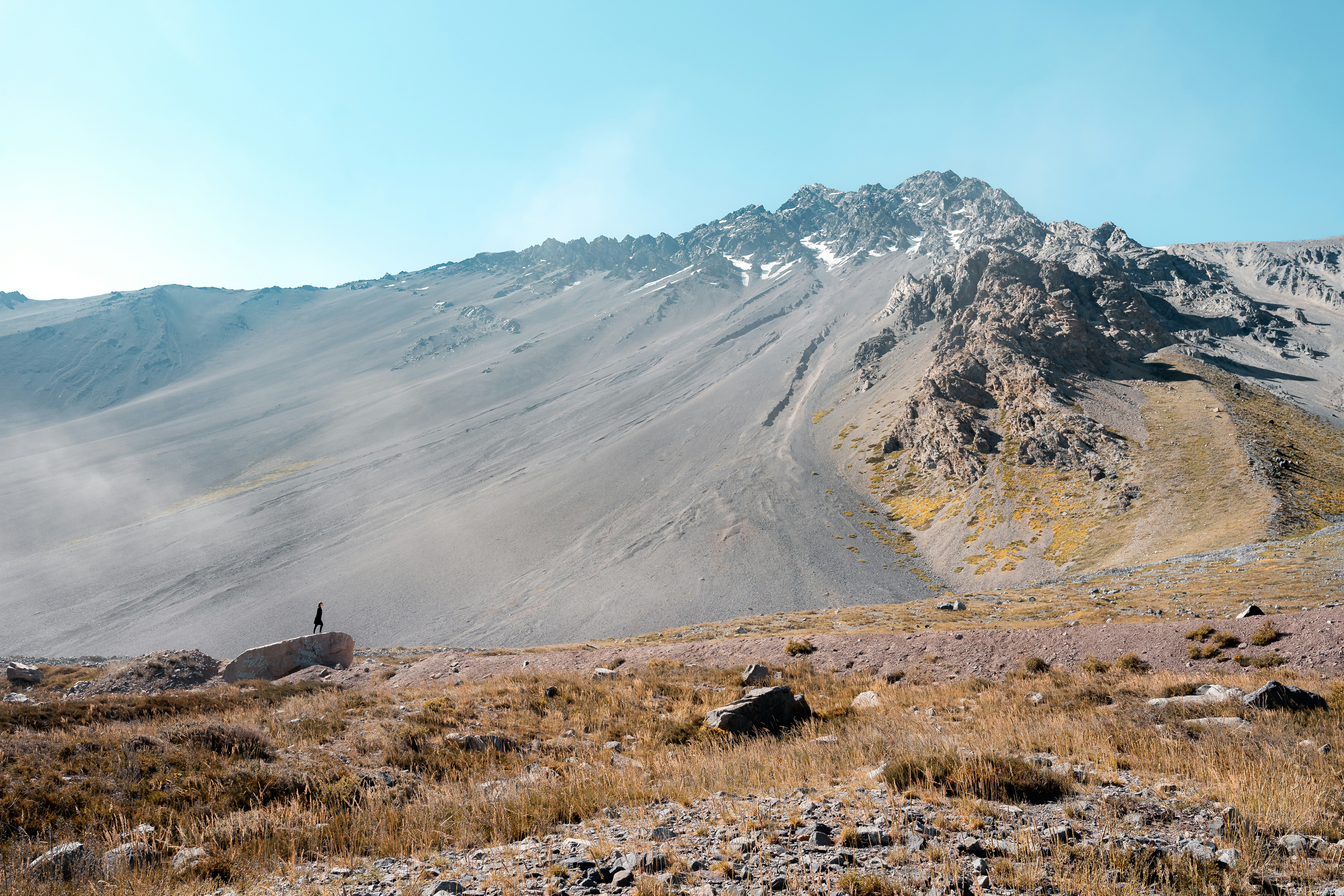 a man standing on top of a dry grass covered hillside