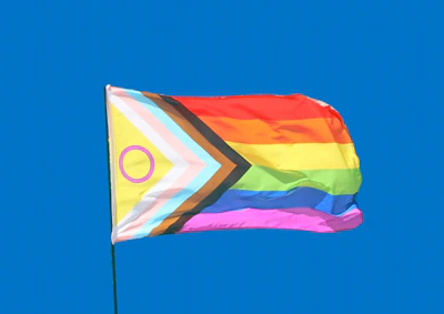 An intersex-inclusive pride flag waving against a solid blue sky