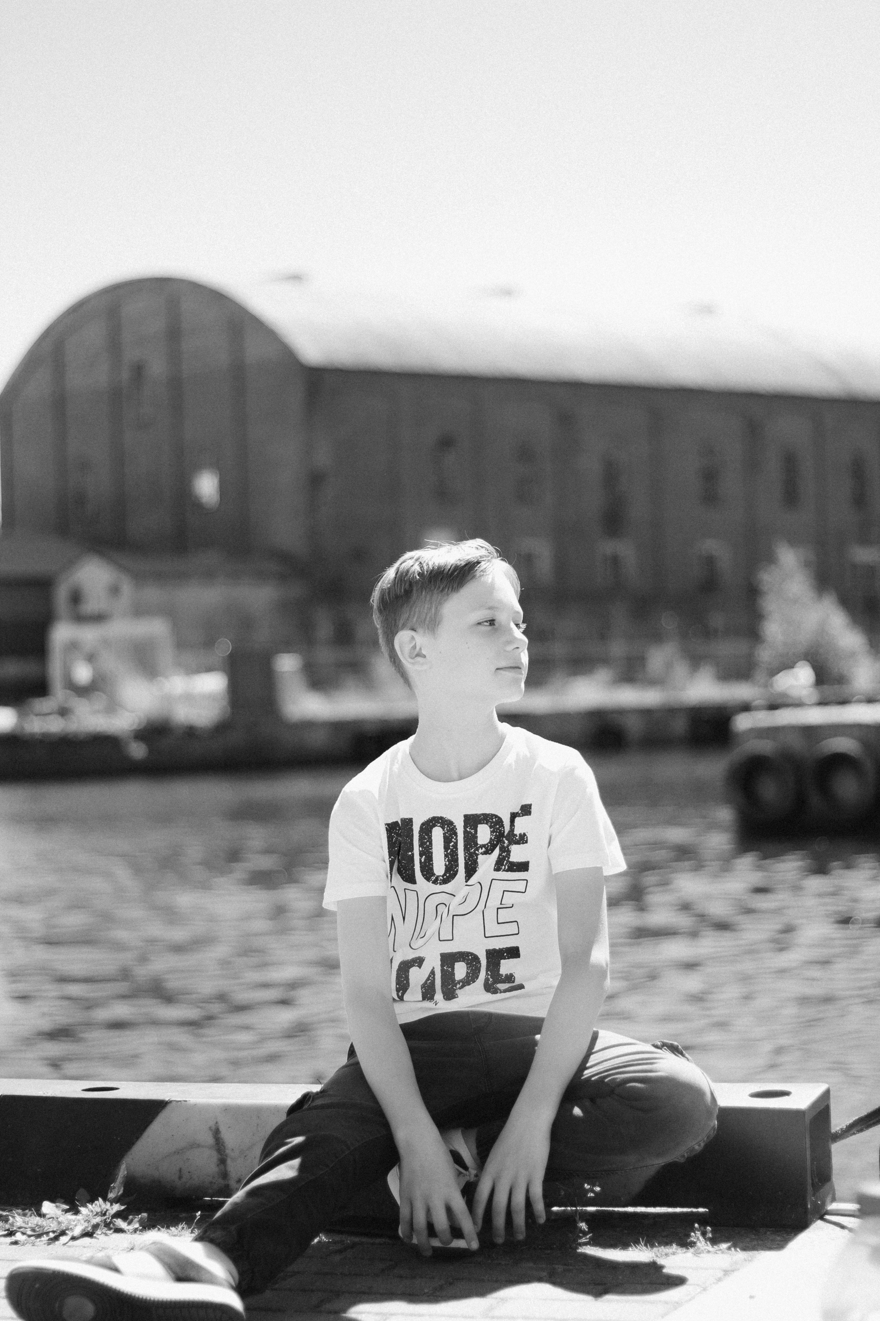 a young boy sitting on the edge of a body of water