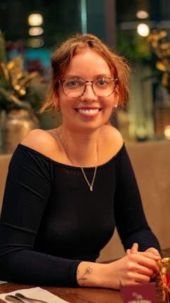 a woman wearing glasses sitting at a table