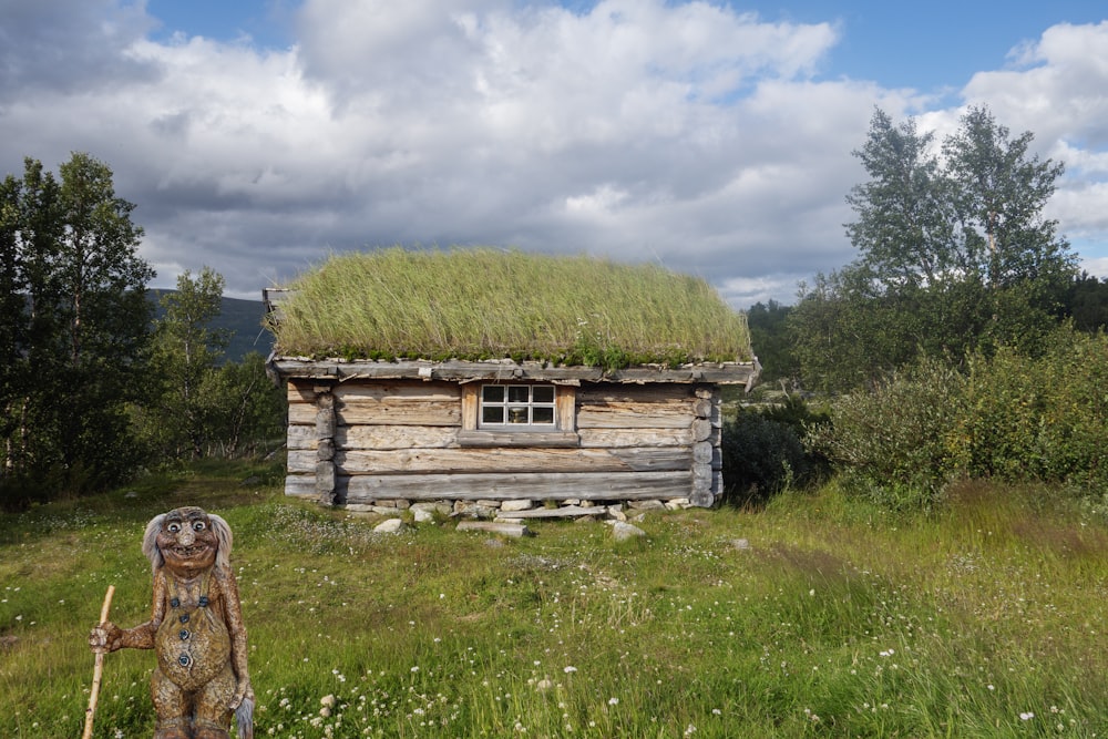 an old log cabin with a grass roof