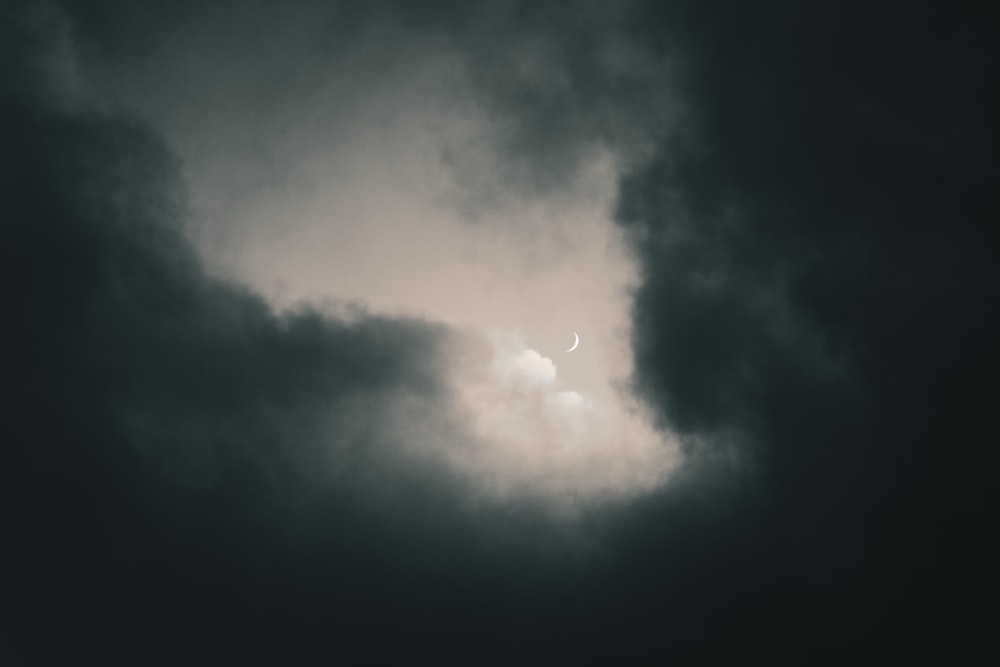 a dark sky with clouds and a half moon
