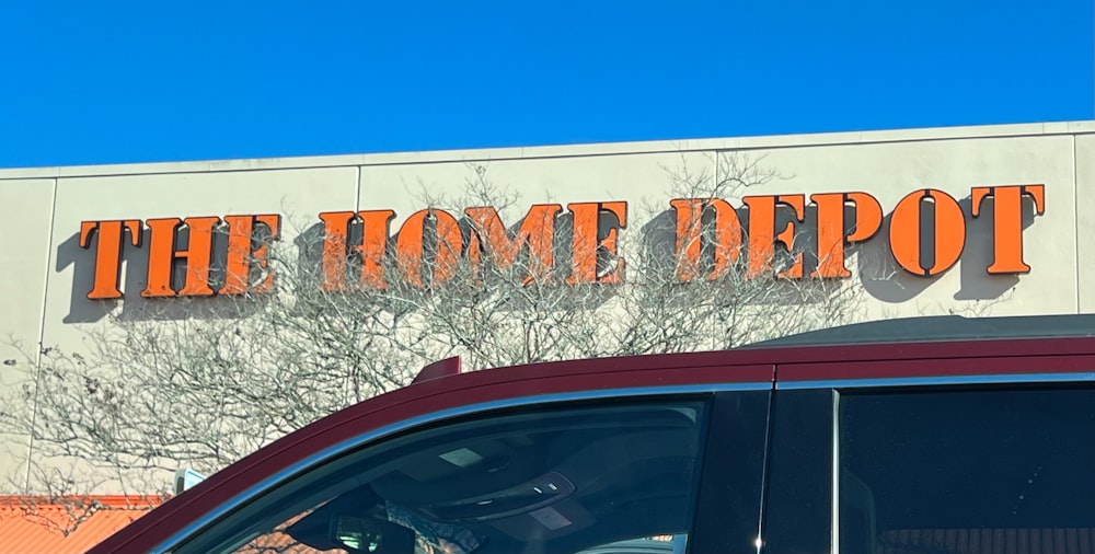 a red car parked in front of a home depot