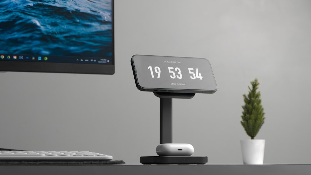 a clock sitting on top of a desk next to a computer monitor