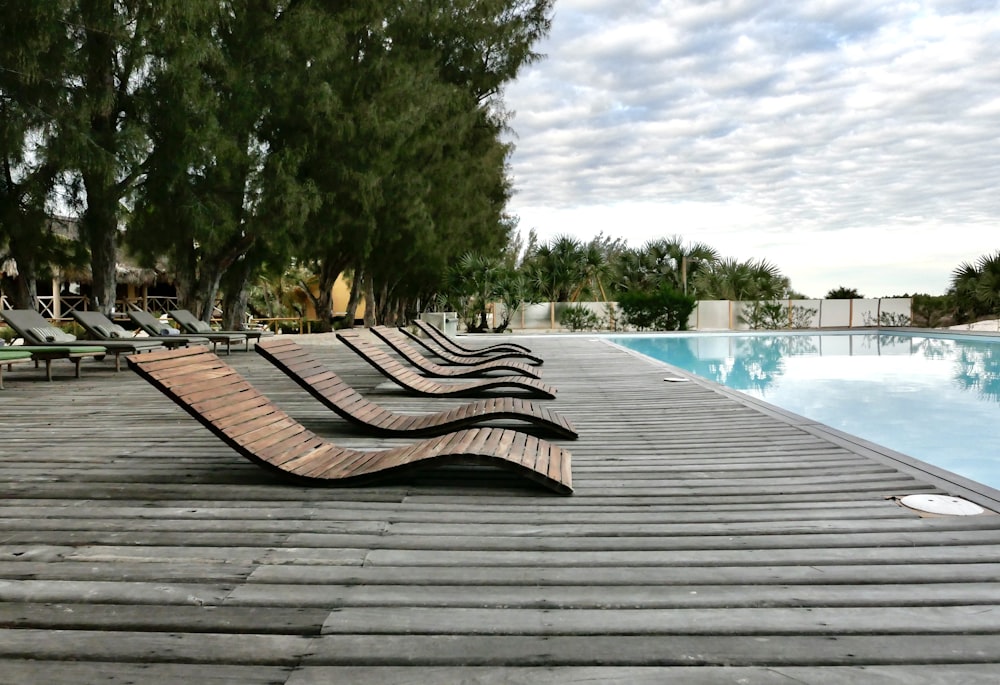 a row of lounge chairs sitting next to a swimming pool