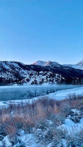 a scenic view of a mountain lake with snow on the ground