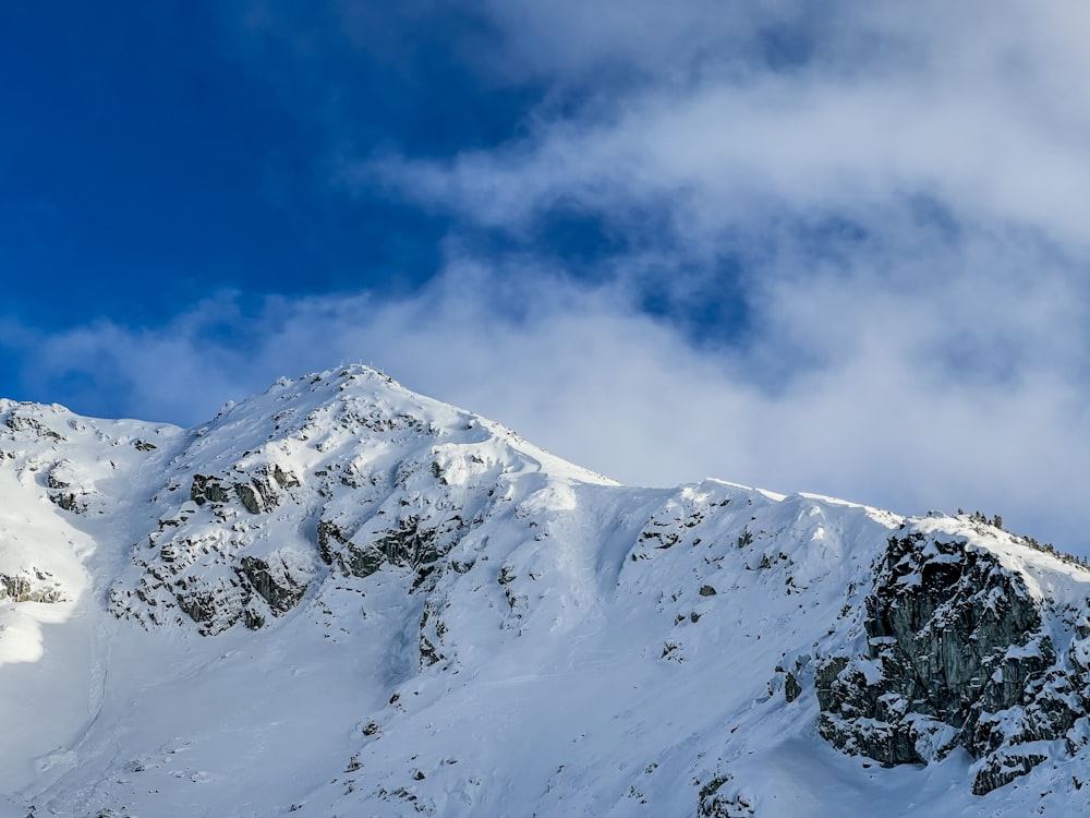 a mountain covered in snow under a cloudy blue sky