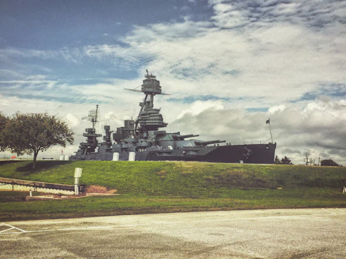 a large battleship sitting on top of a lush green field